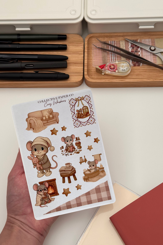 Sheet of decorative stickers featuring cartoon mice and furniture held by a hand, with stationery items in the background.