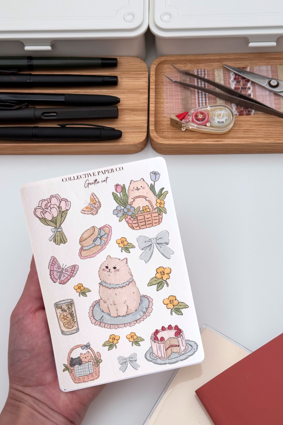 Gentle cat sticker sheet with soft crayon style illustrations of a fluffy cat, flower baskets, bouquet, butterflies, bows, citrus drink and strawberry cake in pastel spring colours from Collective Paper Co