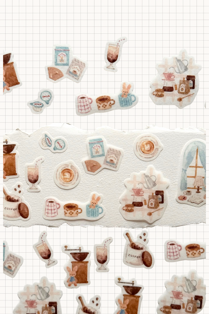 Papier Platz Flake Seal stickers in a soft pink packet, featuring hand-drawn milky drinks, cakes and cosy window scenes with books and lamps on a pale background, shown on grid paper