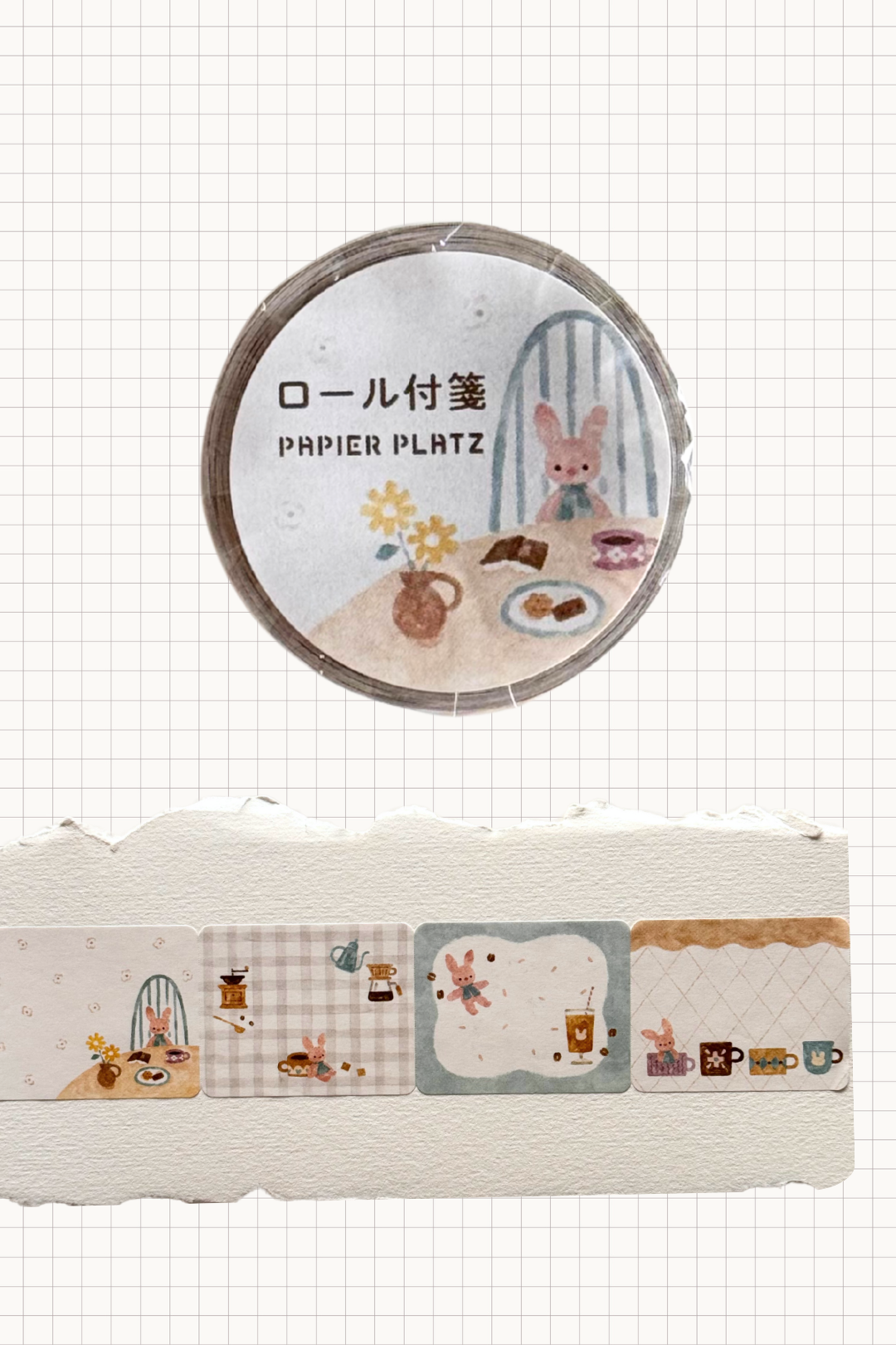 Papier Platz roll sticky notes or masking tape with cosy café scenes featuring a pink bunny, coffee cups and desserts in soft pastel frames, shown on grid background with a row of the rectangular label designs unrolled