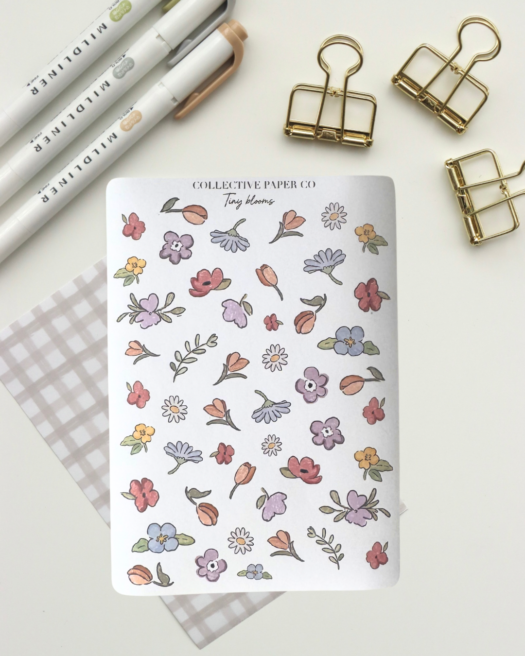 Collective Blooms Co. sticker sheet featuring scattered watercolor-style spring flowers in pink, purple, orange, and white, including tulips, daisies, and violets on a white background.
