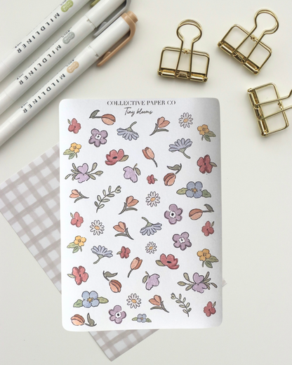 Collective Blooms Co. sticker sheet featuring scattered watercolor-style spring flowers in pink, purple, orange, and white, including tulips, daisies, and violets on a white background.
