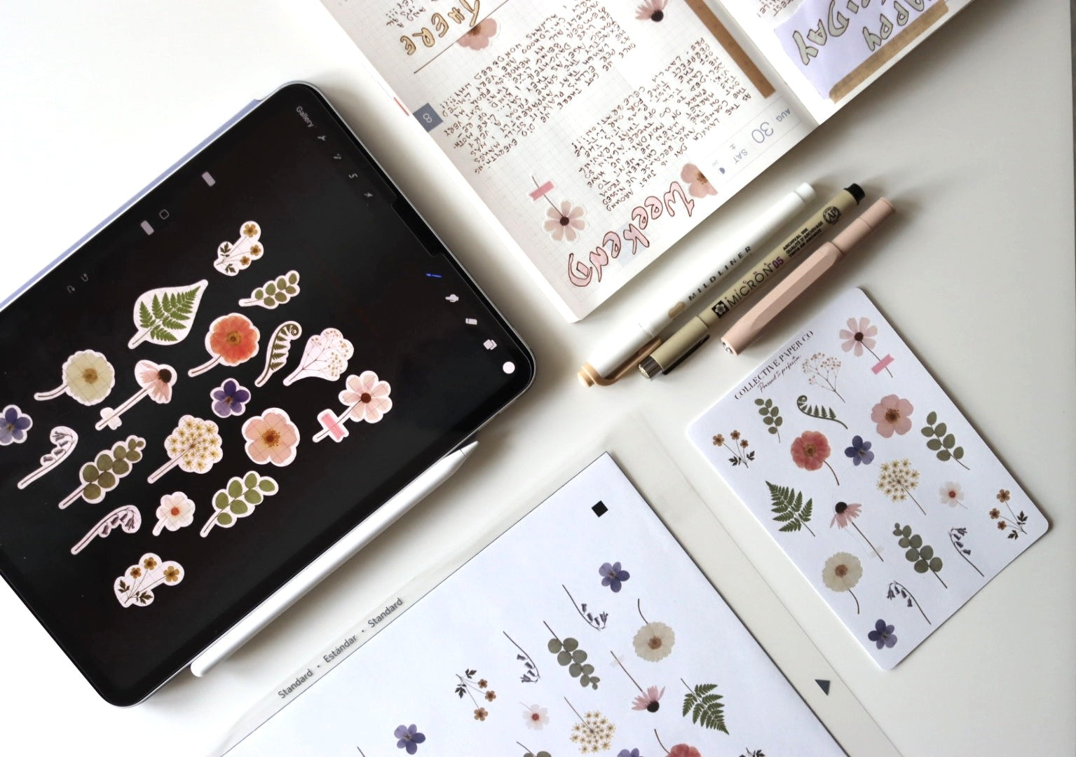 Flay lay photo showcasing how stickers are designed, printed and cut, and stuck into a journal